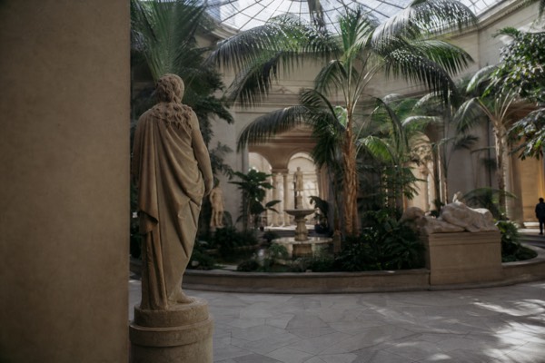 Palm-filled domed winter garden inside a Copenhagen art museum with sculptures around the fountain